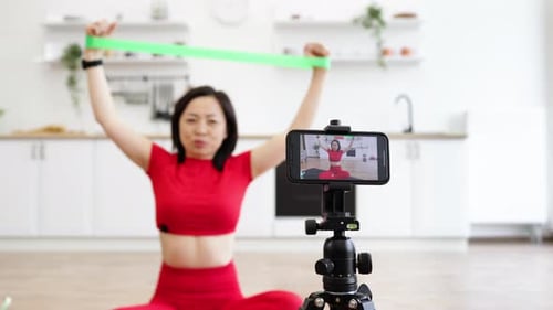 Woman Exercising With Resistance Band, Recording on Phone