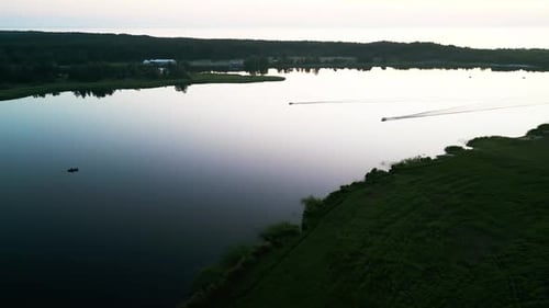 Aprecie a vista aérea pacífica de um lago sereno ao entardecer com barcos graciosamente em movimento pelo
