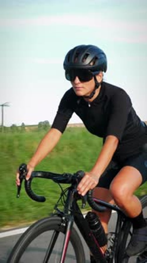 Cyclist riding bicycle on asphalt road at sunny summer day. Vertical video