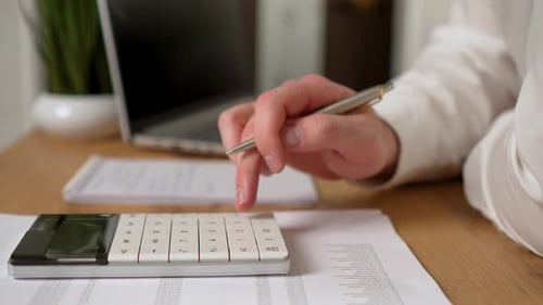 Businessman Working in Office Calculating Financial Reports Organizing Paperwork Using Laptop and