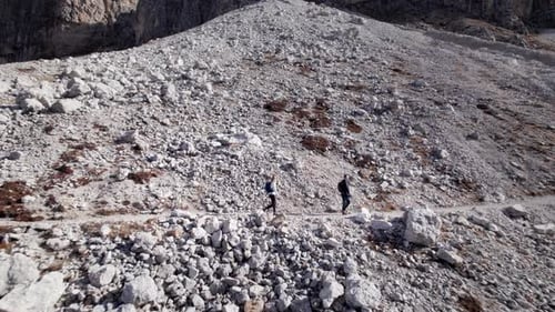 Moving away shot of two people walking the path in mountains