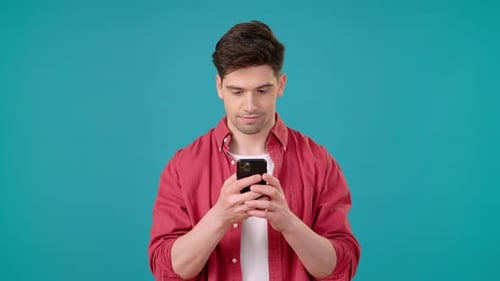 Excited Man Uses Phone on Teal Background