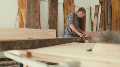 Schreiner misst Holzbrett in seiner Werkstatt