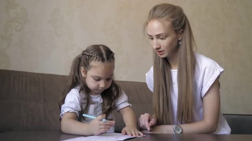 Woman and Child Drawing Together at Table Indoors