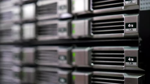 Close-up of 4TB hard drives in a server rack, green status lights on. Excellent for showing data sto