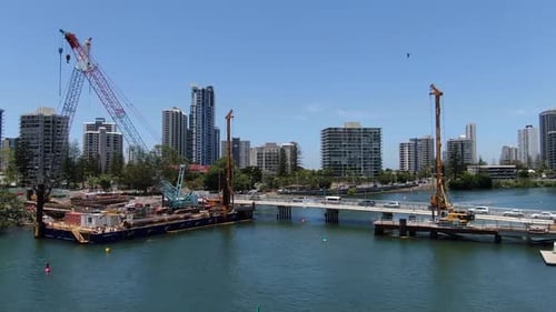 Crane on Bridge Construction Crossing Islands with City Backdrop