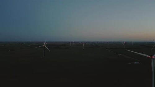 Aerial Wide Shot of a Close Up Wind Turbine Standing in a Wheat Field at Night Time