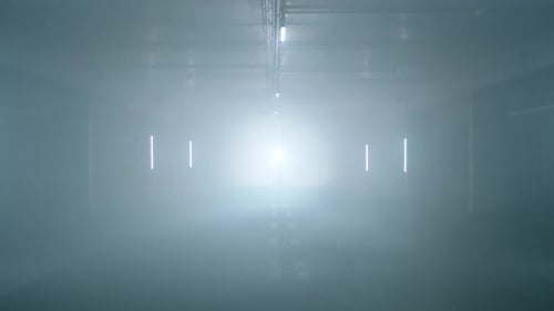 Fog fills an eerie and bright concrete tunnel