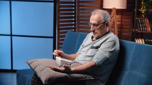 Man Checking Blood Pressure at Home on Couch