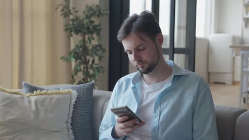 Young Man Using Phone on a Couch Indoors