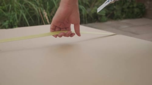 Handheld shot of opening a big package outside on the terrace. Female caucasian hands holding a box
