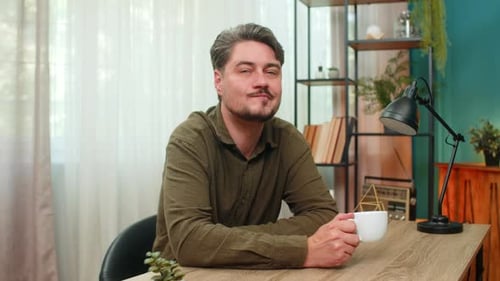 Man drinking and contemplating at his desk