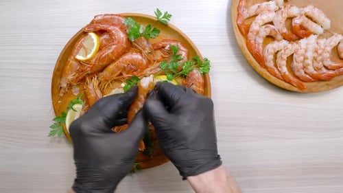 Cooked Shrimp Being Peeled by a Person Wearing Gloves