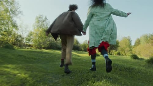 Carefree Couple Holding Hands and Running through Green Field