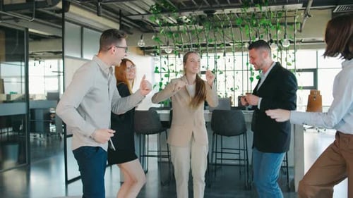 Enthusiastic Team Celebrating Success with Dance in Office