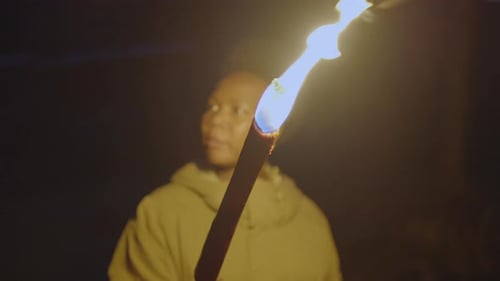 Young Adult Holds a Burning Torch at Night