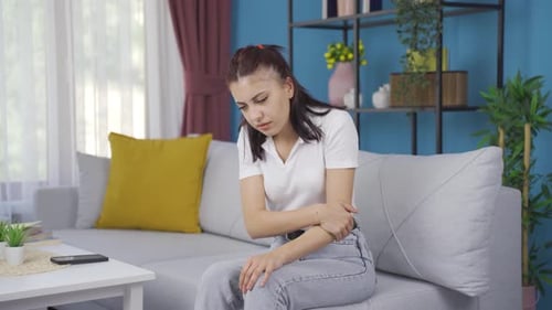 Young Woman Experiencing Arm Pain on Couch