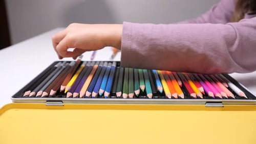 Child Drawing with Colored Pencils at a Table