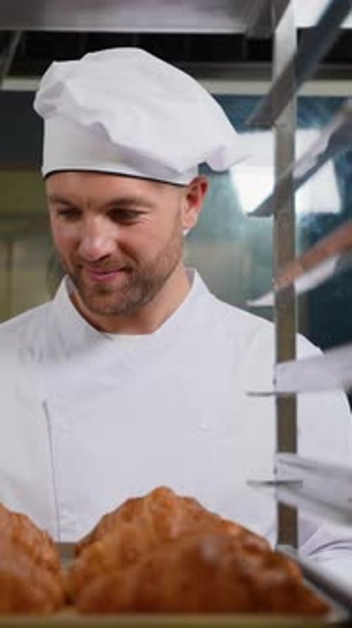 Smiling Baker Holding Fresh Croissants in Commercial Kitchen