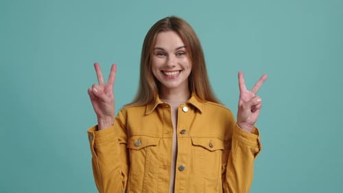 Portrait d'une jeune femme aux cheveux blonds faisant un signe de victoire
