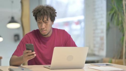 Young Adult Concentrates on Smartphone at Desk