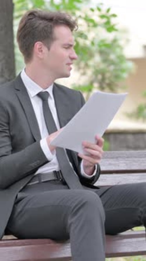 Serious Man in Suit Reviews Documents on Bench