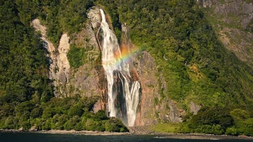 Rainbow shining on huge waterfall in Milford Sound. Spectacular landscape surrounding Lady Bowen, Mi