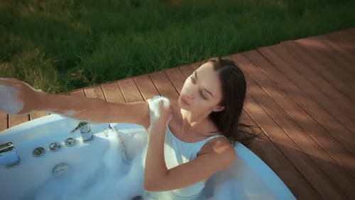 Woman Relaxes in Jacuzzi with Bubbles Outside