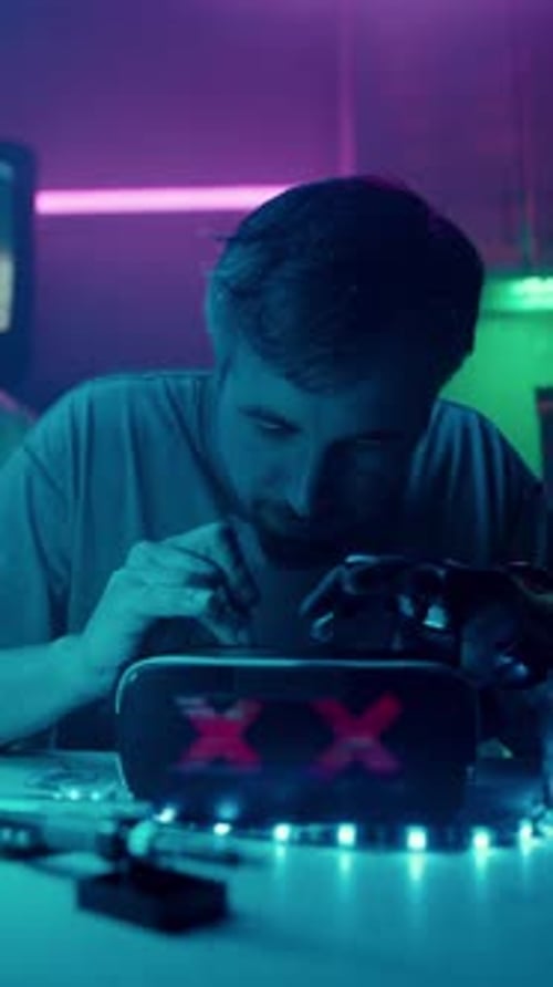 Young Man Works on Robotic Arm at Night