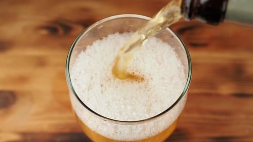 Pouring beer from a bottle into a glass.