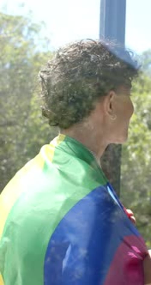 Young Adult Smiling with Pride Flag at Window