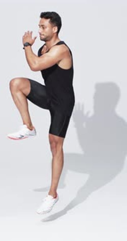 Vertical video: Biracial male athlete running in place, white background