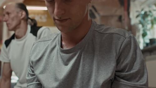 Young Man Stretching Arms before Wall Climbing Training Indoors