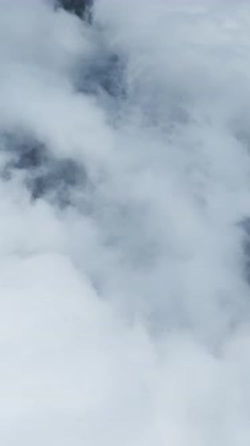 Vertical Video Misty Clouds Rest Above a Dense Mountain Forest Offering a Scenic and Tranquil View