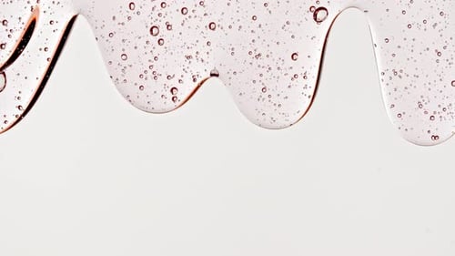 Transparent Cosmetic Gel Fluid With Molecule Bubbles Flowing On The Plain White Surface