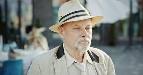 Senior Man in Hat Standing Outdoors on Sunny Day