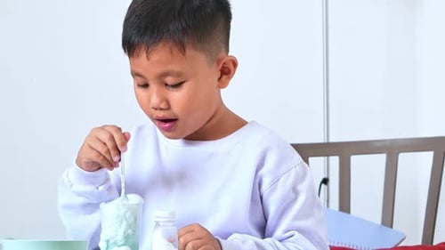 Un niño pequeño parece sorprendido mientras agita un experimento científico con espuma azul