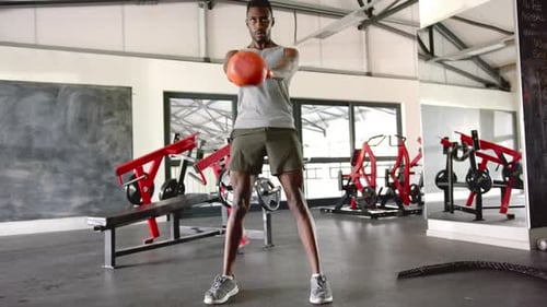 Lifting kettlebell, african american man working out in gym, focusing on strength training
