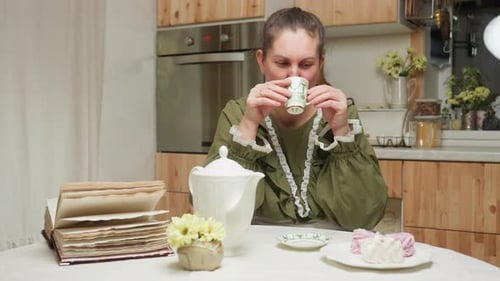 Woman Enjoys Tea at Kitchen Table Indoors