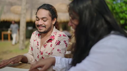Diverse Friends Explore Menu at Sunny Outdoor Cafe Gay BIPOC Group Enjoys Al Fresco Dining