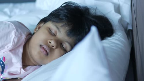 Child Sleeps Peacefully on White Bedding