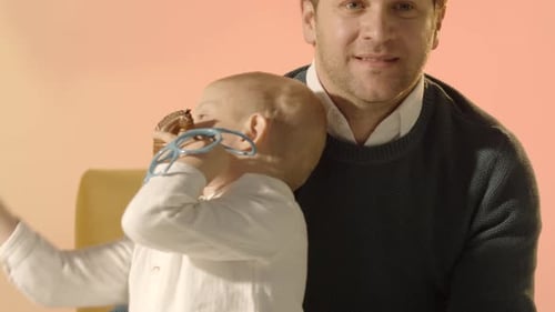 Baby gnawing glasses in an adult's arms