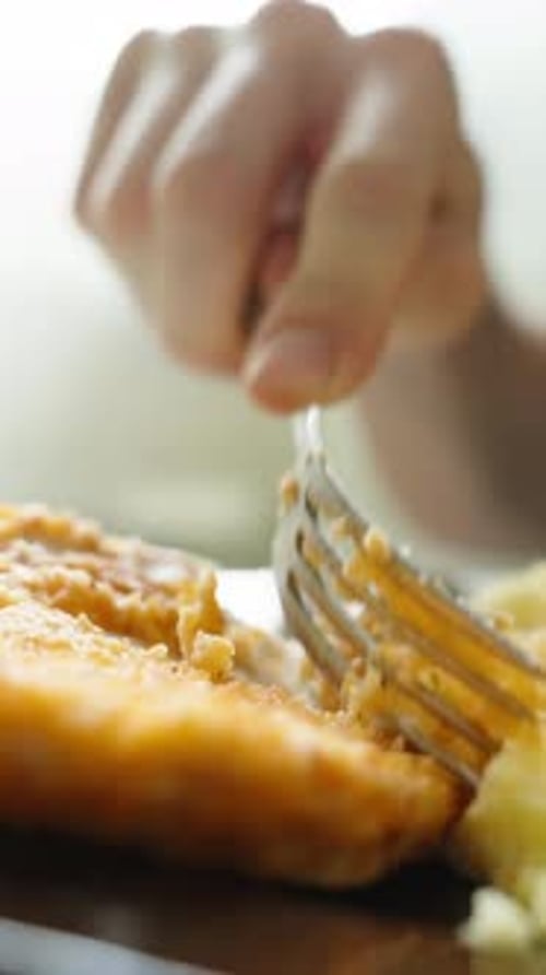 Ein Mann isst ein Hühnersteak mit Kartoffeln, in der Sonne, Nahaufnahme. Vertikales Video.