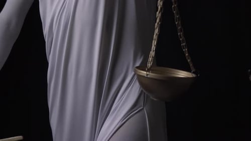 Statue of Lady Justice Holding Scales in Dark