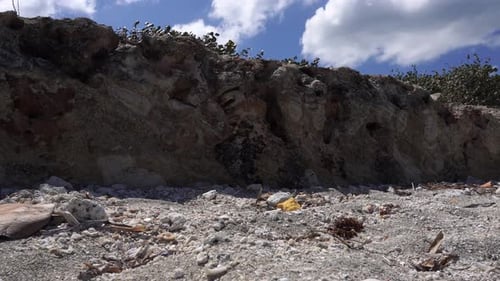 A miniature rock reef on the edge of a beach with many small rock fragments on the ground