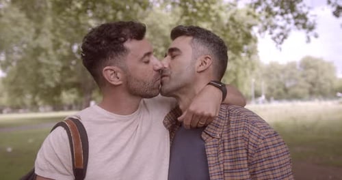 Adult male couple kissing in a park