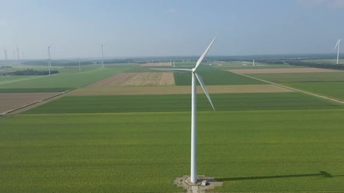 Jib down of spinning wind turbine in a large windmill park in green meadows