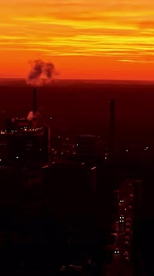 Sunset Over Industrial Plant, Smoke Rising in Orange Glow