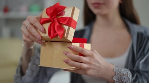 Woman Opens a Gift Box Tied with Ribbon