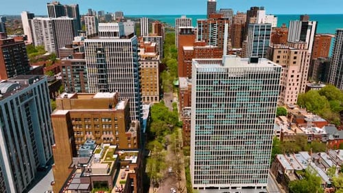 Flight over the green street among the beautiful high-rise buildings.
